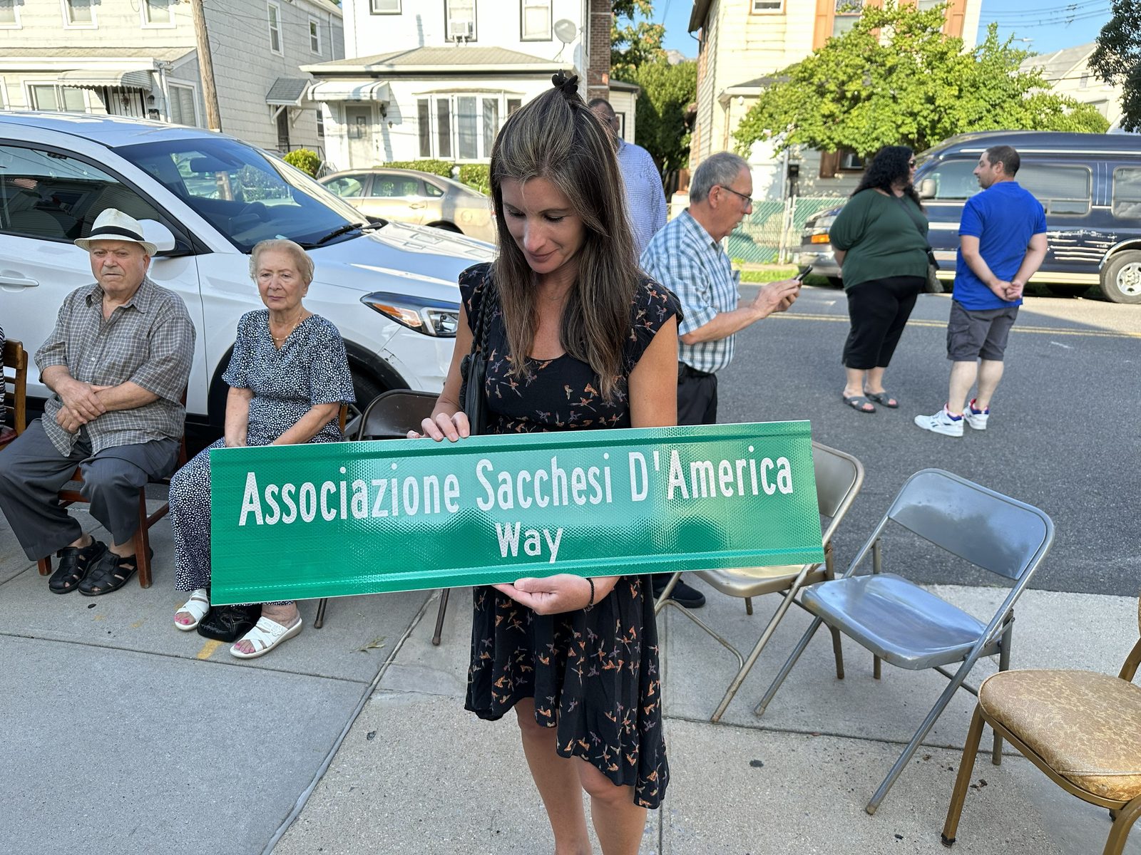 A member holds the Associazione Sacchesi D'America Way street sign